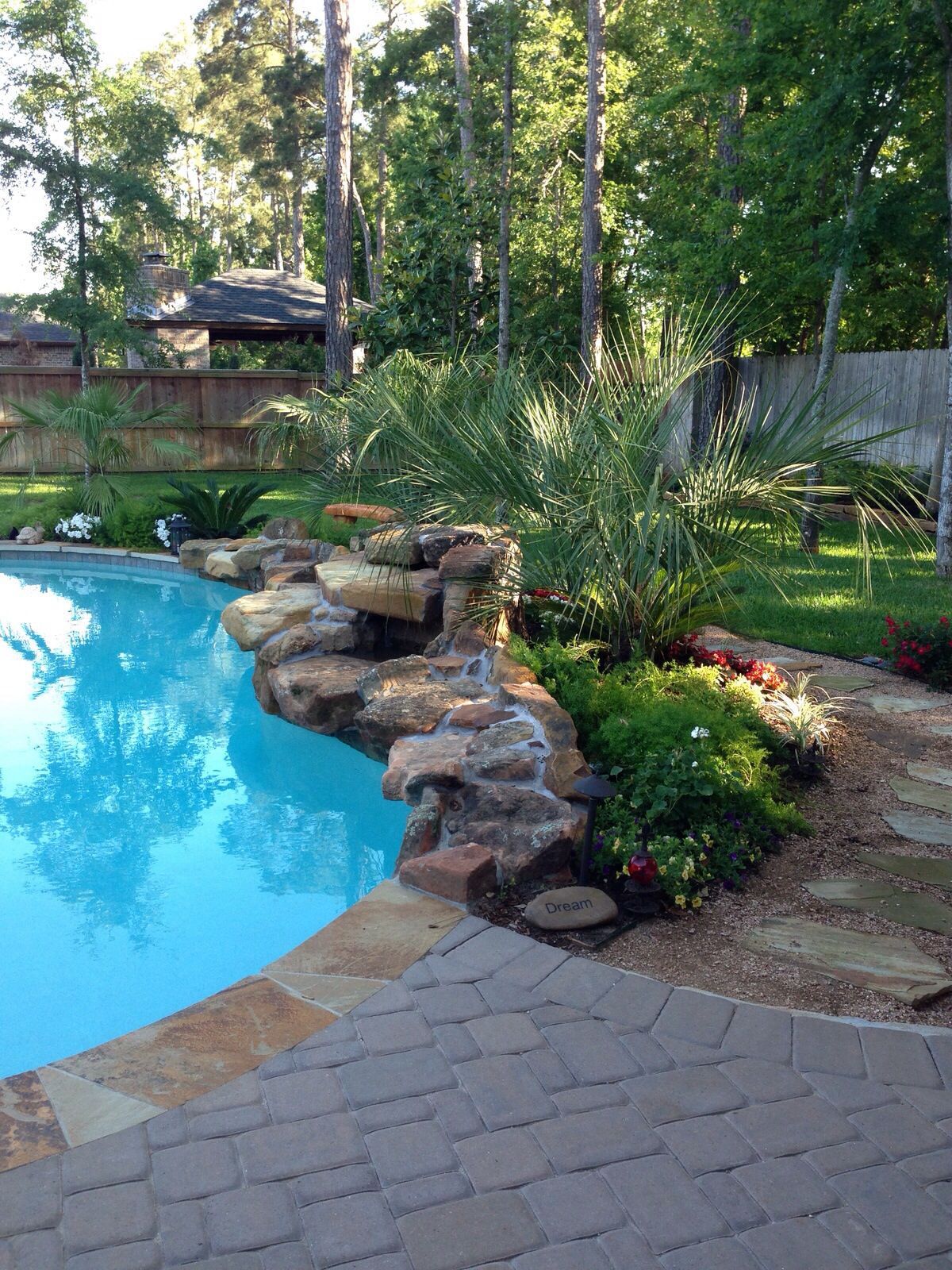 Beautiful "poolscaping" - Rock waterfall in front of lush plants | Pool